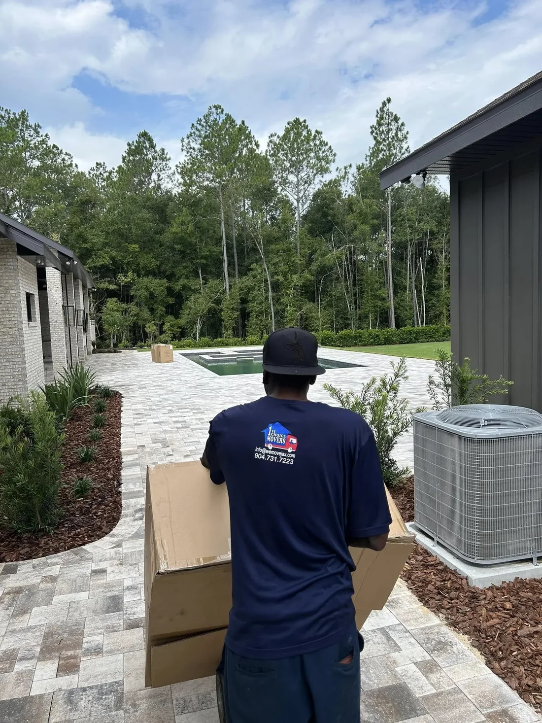 1st Choice Movers team member carrying moving boxes outside a home